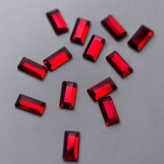 Zoom sur le strass dentaire Swarovski rouge en forme de baguette. Détails et brillance.