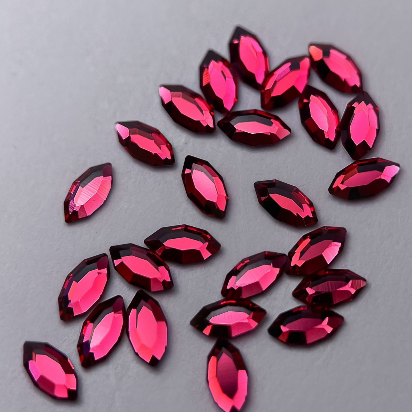 Zoom sur strass dentaire Swarovski en forme de navette, couleur cherry, haute brillance, qualité professionnelle.