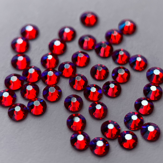 Zoom sur strass rond fuchsia aux reflets arc-en-ciel.