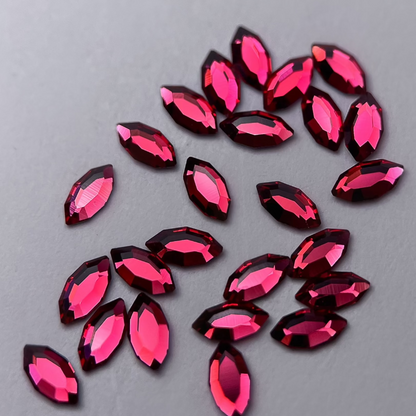 Zoom sur strass dentaire Swarovski en forme de navette, couleur cherry, haute brillance, qualité professionnelle.