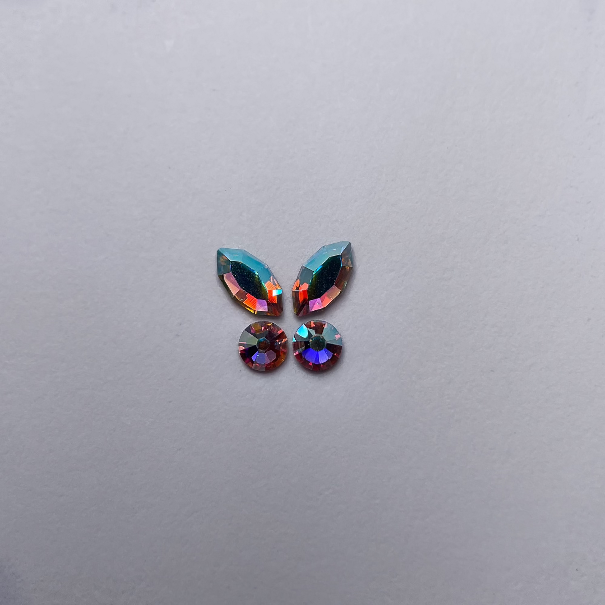 Papillon formé de deux strass navette et deux strass ronds, couleur holographic assortie.